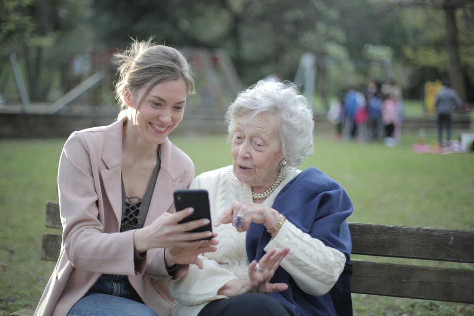 Oudere en jongere vrouw kijken op een smartphone