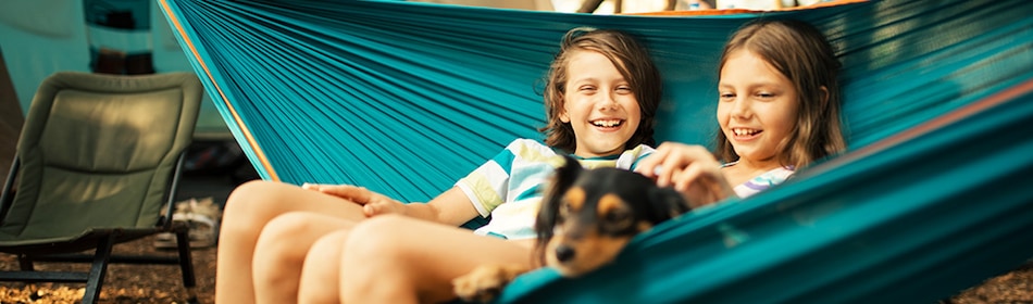 2 kinderen en een hond in hangmat voor de tent