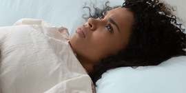 Vrouw ligt wakker in bed naar plafond te staren