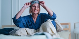 Vrouw in bed met slaapmasker op hoofd