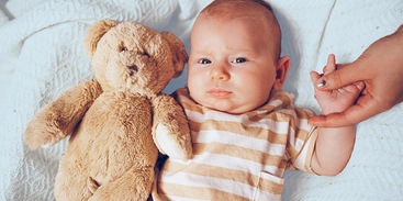 baby met knuffel in bed