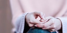 Vrouw wrijft met één hand over haar nagels, ze lijkt ingetogen